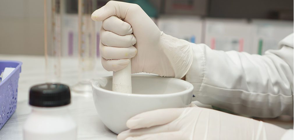 pharmacist preparing medication with a mortar and pestle to grind pills or a pill