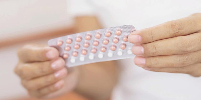 Woman opening birth control pills in hand.