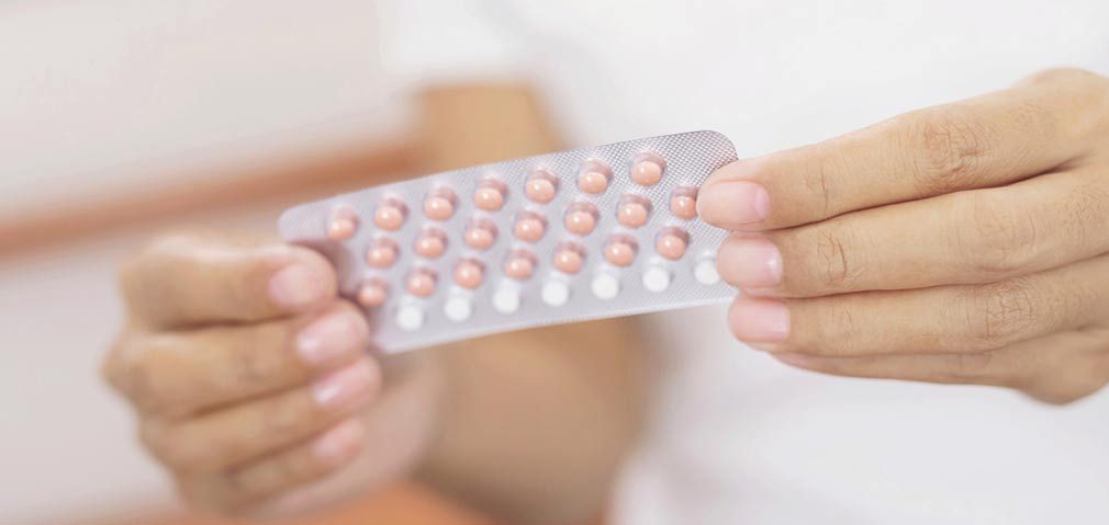 Woman opening birth control pills in hand.